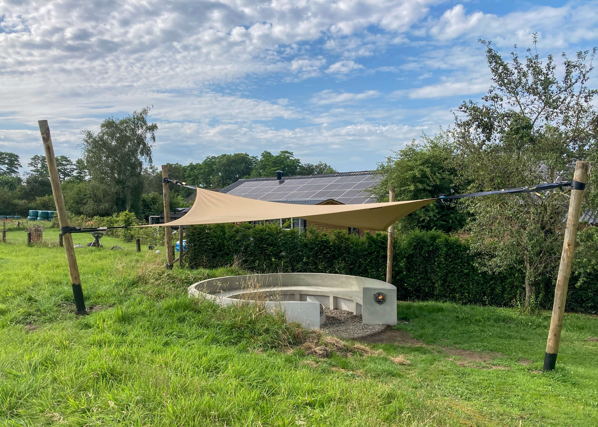 Zandkleurige tuinoverkapping boven vuurpit in de tuin
