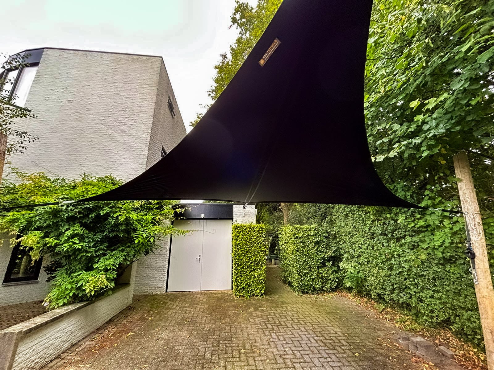 Zwarte tuinoverkapping van stretchtent doek op een oprit